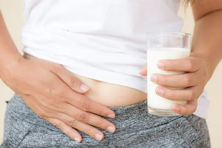 Frau hält Bauch mit Milchglas in der Hand