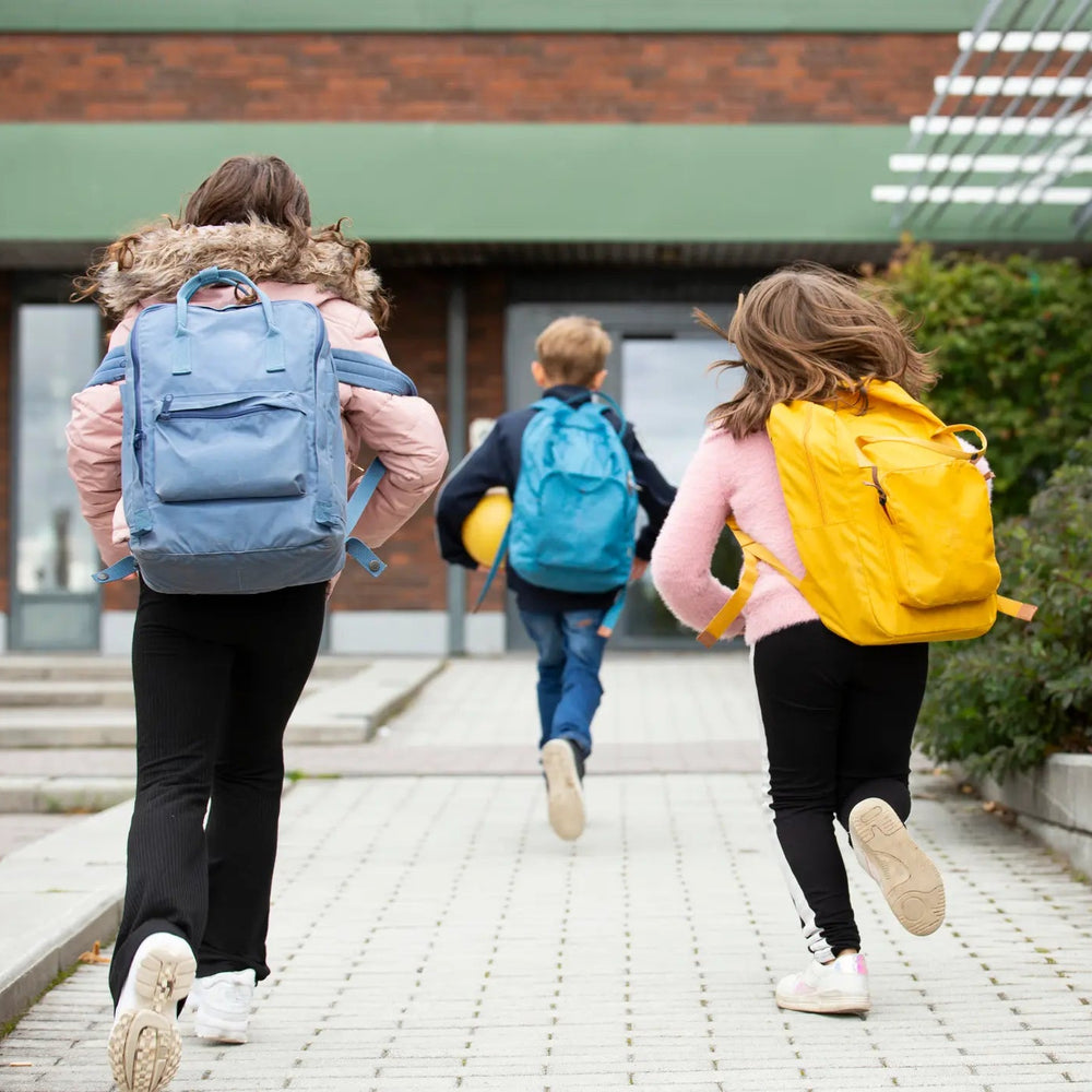 Kinder rennen mit ihren Rucksäcken auf dem Rücken auf eine Tür zu