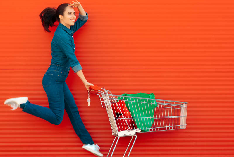 Frau mit Einkaufswagen vor roter Wand